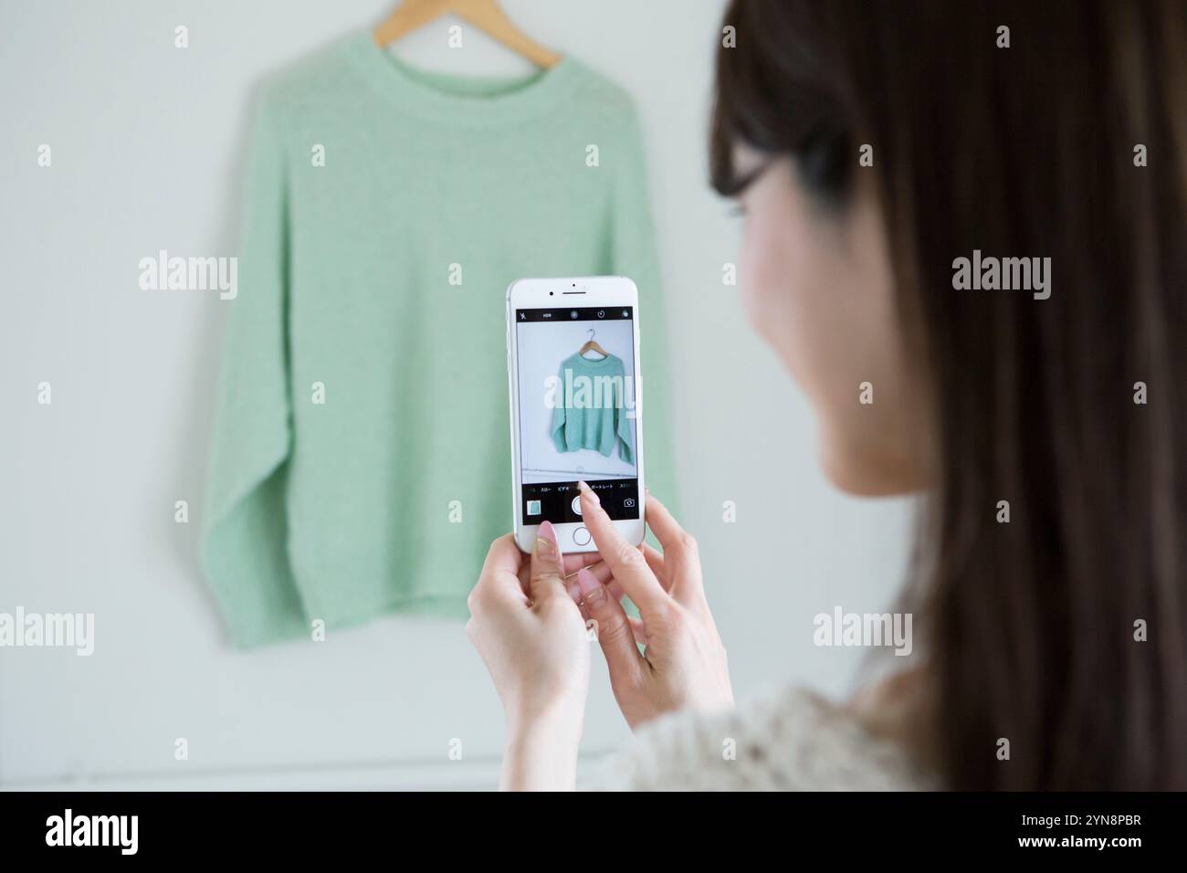 Woman taking a photograph of a piece of clothing Stock Photo