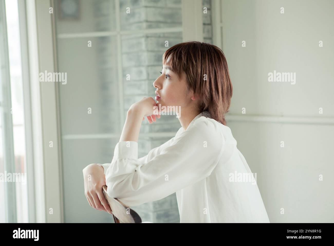 Profile of a woman in her 20s sitting on a chair Stock Photo - Alamy