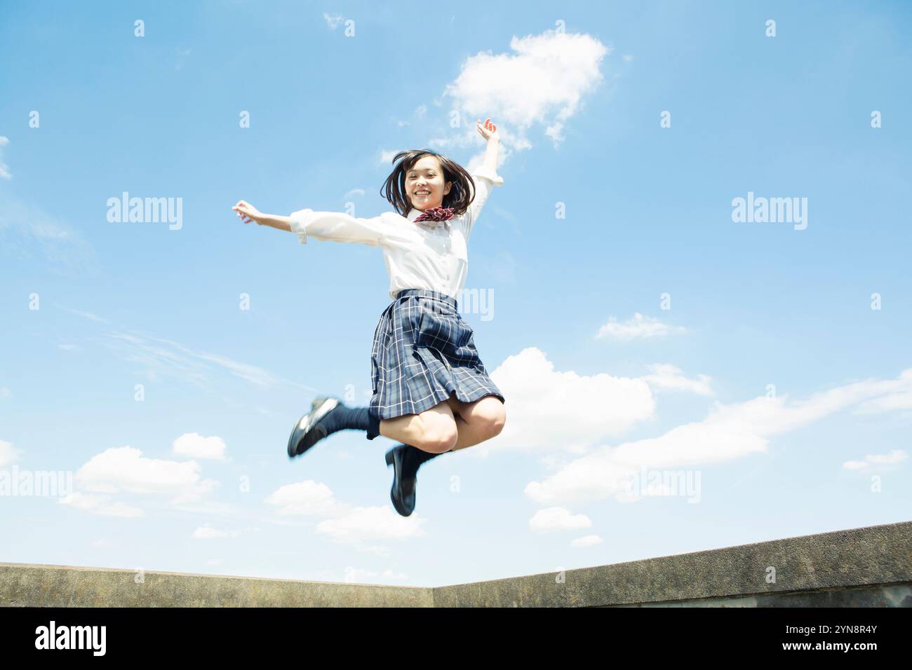 High school girl jumping under a blue sky Stock Photo - Alamy