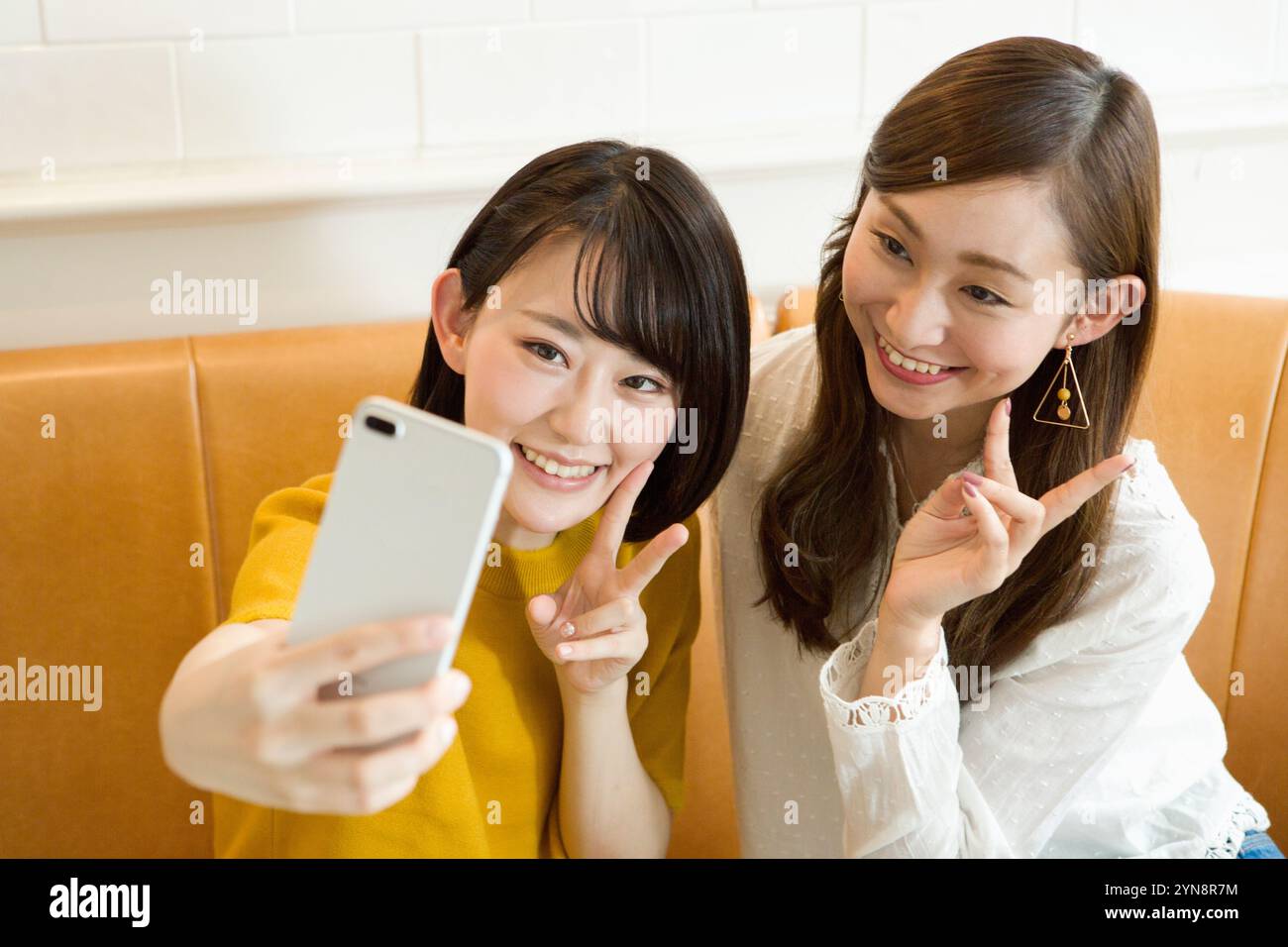 Two girls in their 20s taking selfies on their phones Stock Photo - Alamy