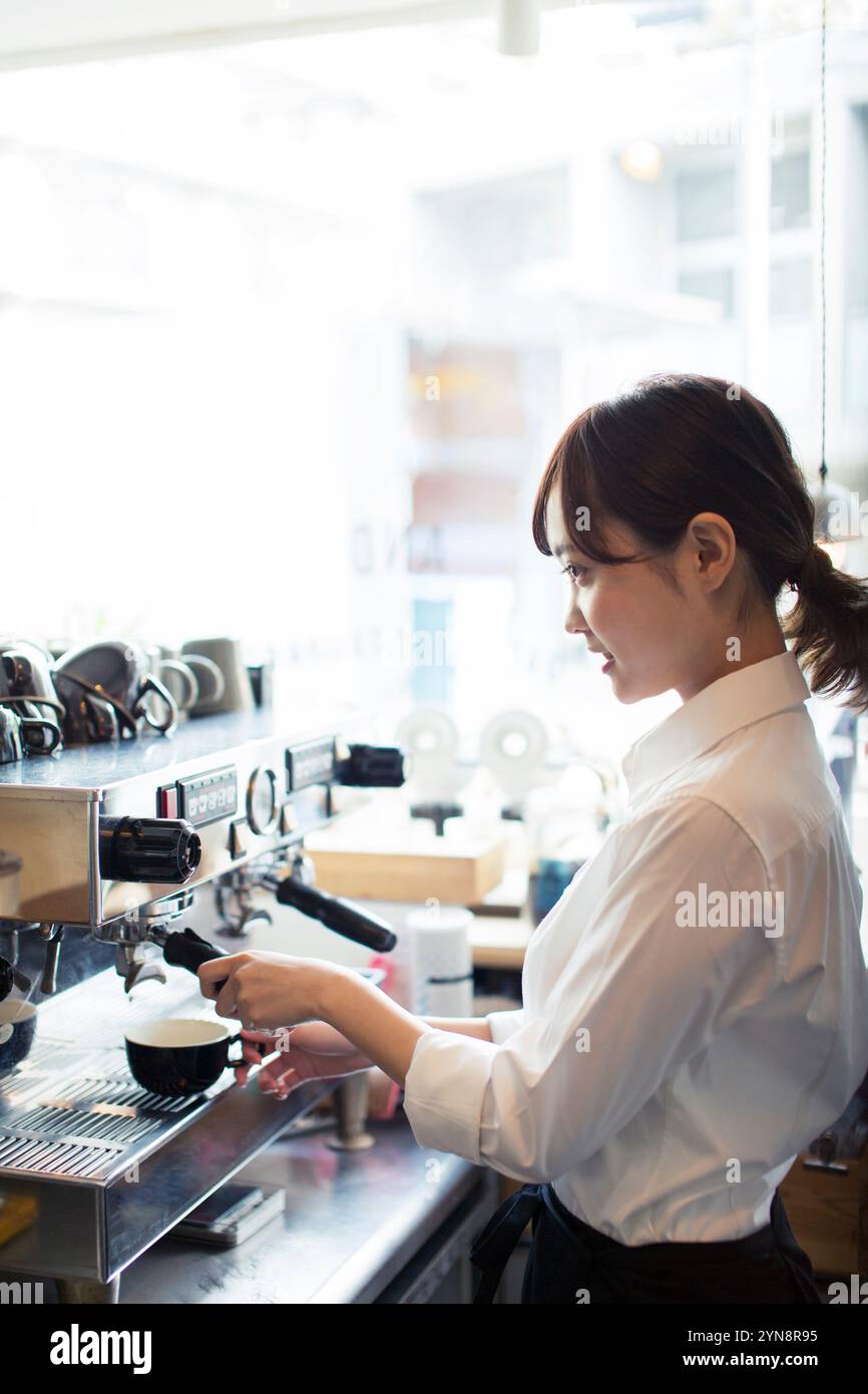 20-something café worker making coffee Stock Photo