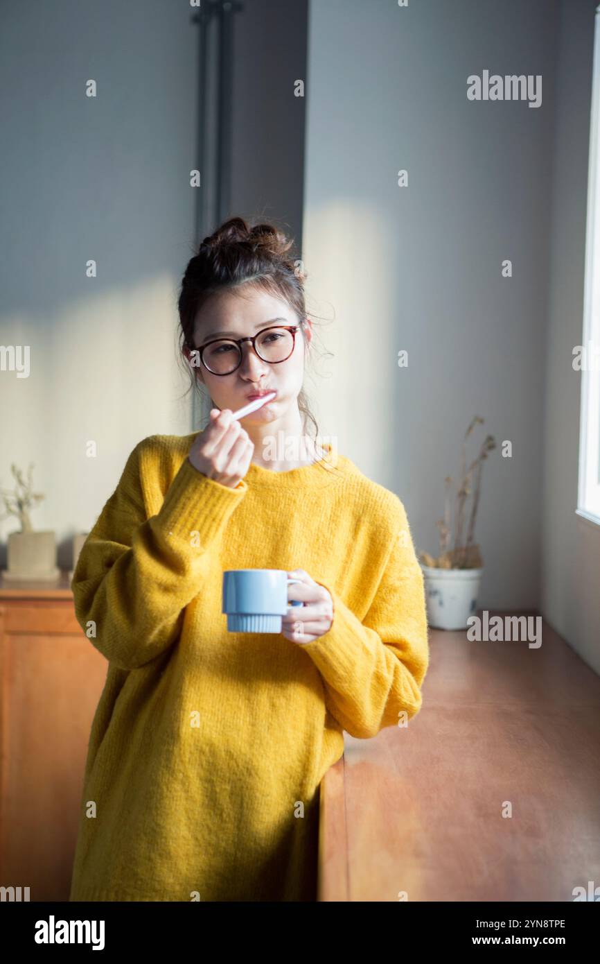 Woman in her 20s brushing her teeth by the window Stock Photo - Alamy