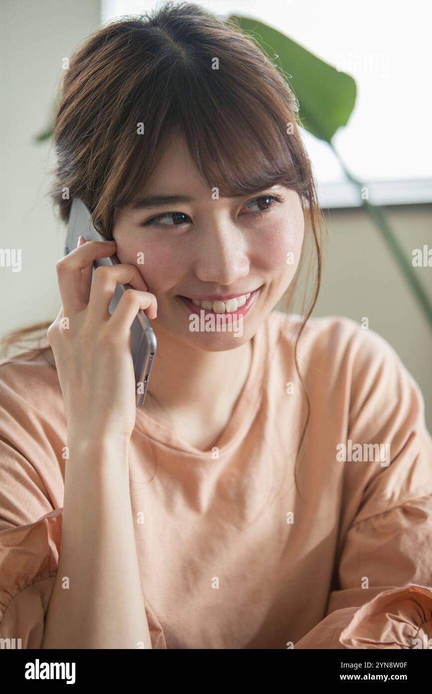 Smiling 20s woman making a phone call in her room Stock Photo - Alamy