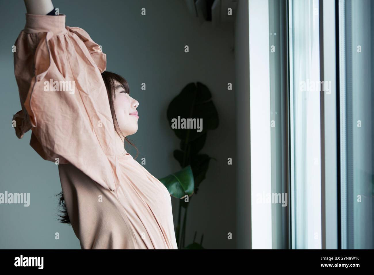 Woman in her 20s stretching out by the window in profile Stock Photo ...