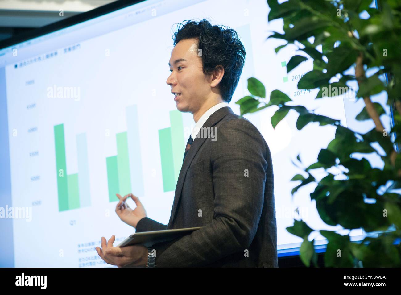 Smiling man in his 20s showing and explaining a graph Stock Photo - Alamy