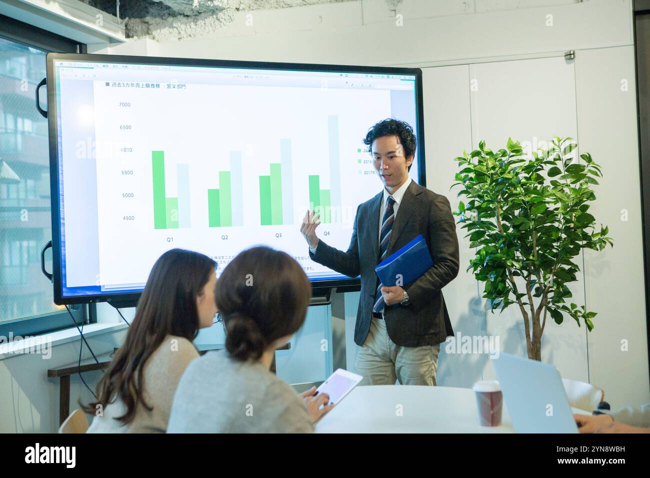 Smiling man in his 20s showing and explaining a graph Stock Photo - Alamy