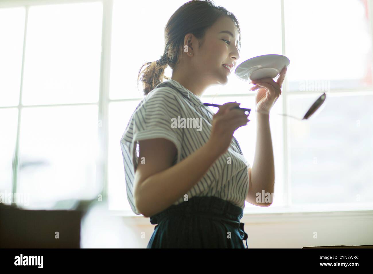 Woman in her 20s in profile tasting food Stock Photo - Alamy
