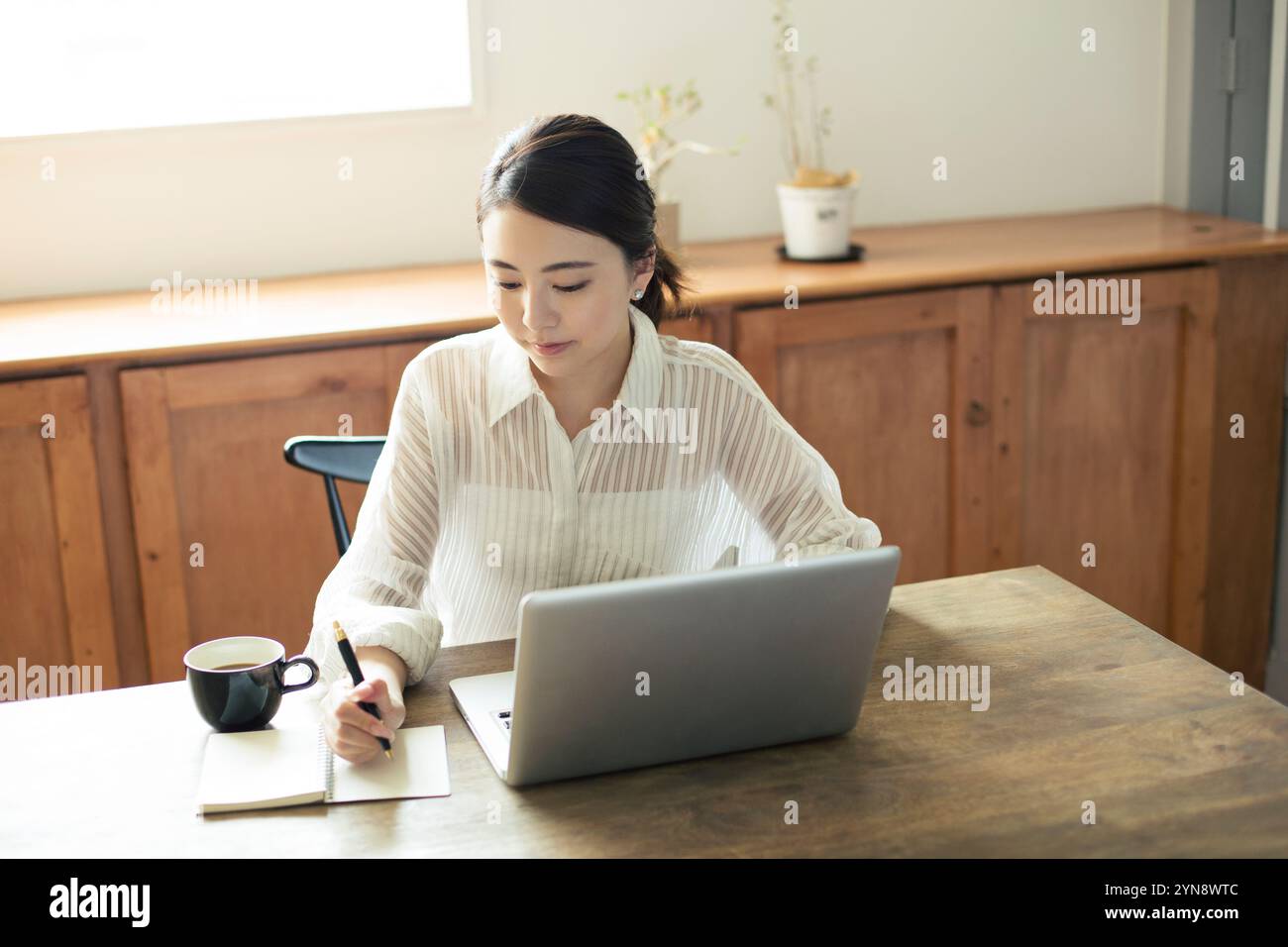 Woman in her 20s sitting by the window working Stock Photo - Alamy