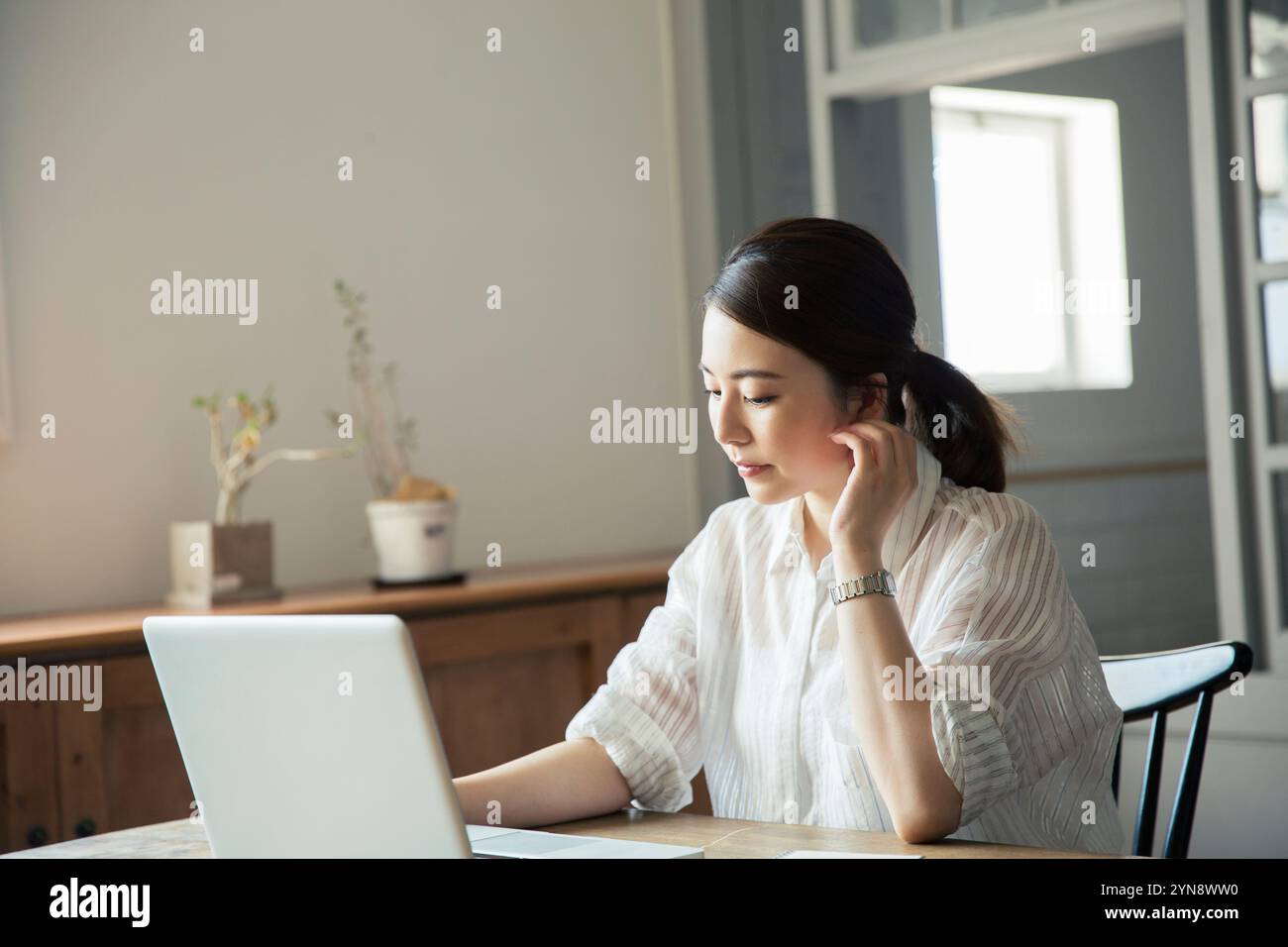 Woman in her 20s operating a computer by the window Stock Photo - Alamy