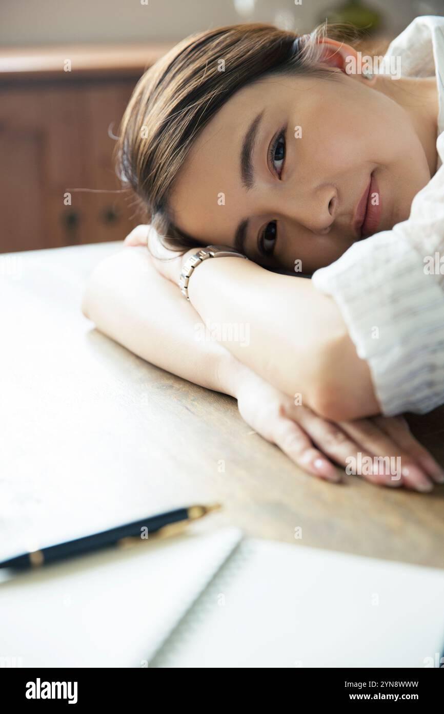 Woman in her 20s looking at the camera leaning against a desk Stock ...