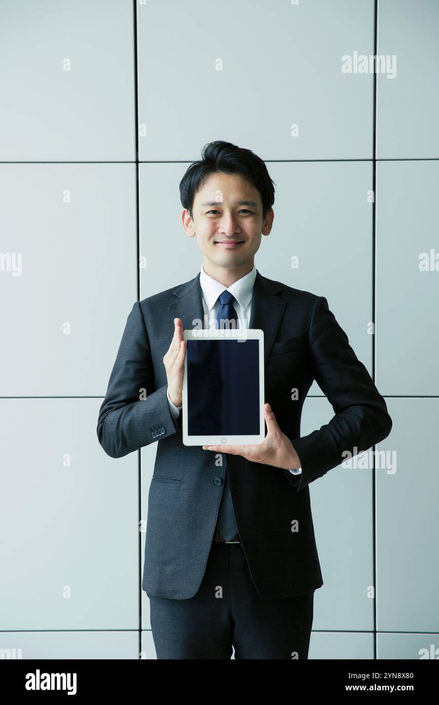 Man in his 20s in suit holding tablet Stock Photo - Alamy
