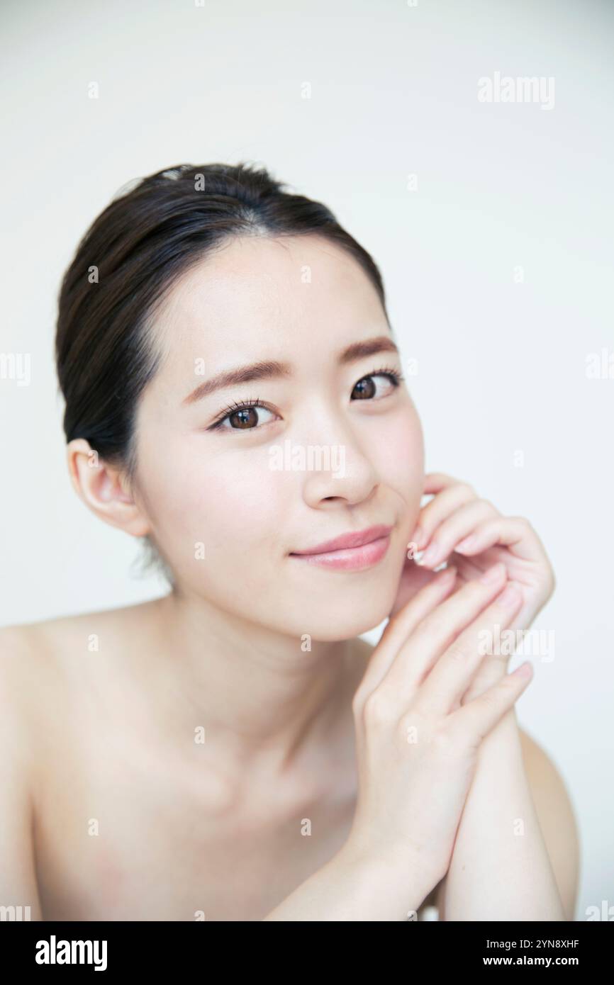 Woman in her 20s smiling with hand on cheek Stock Photo - Alamy