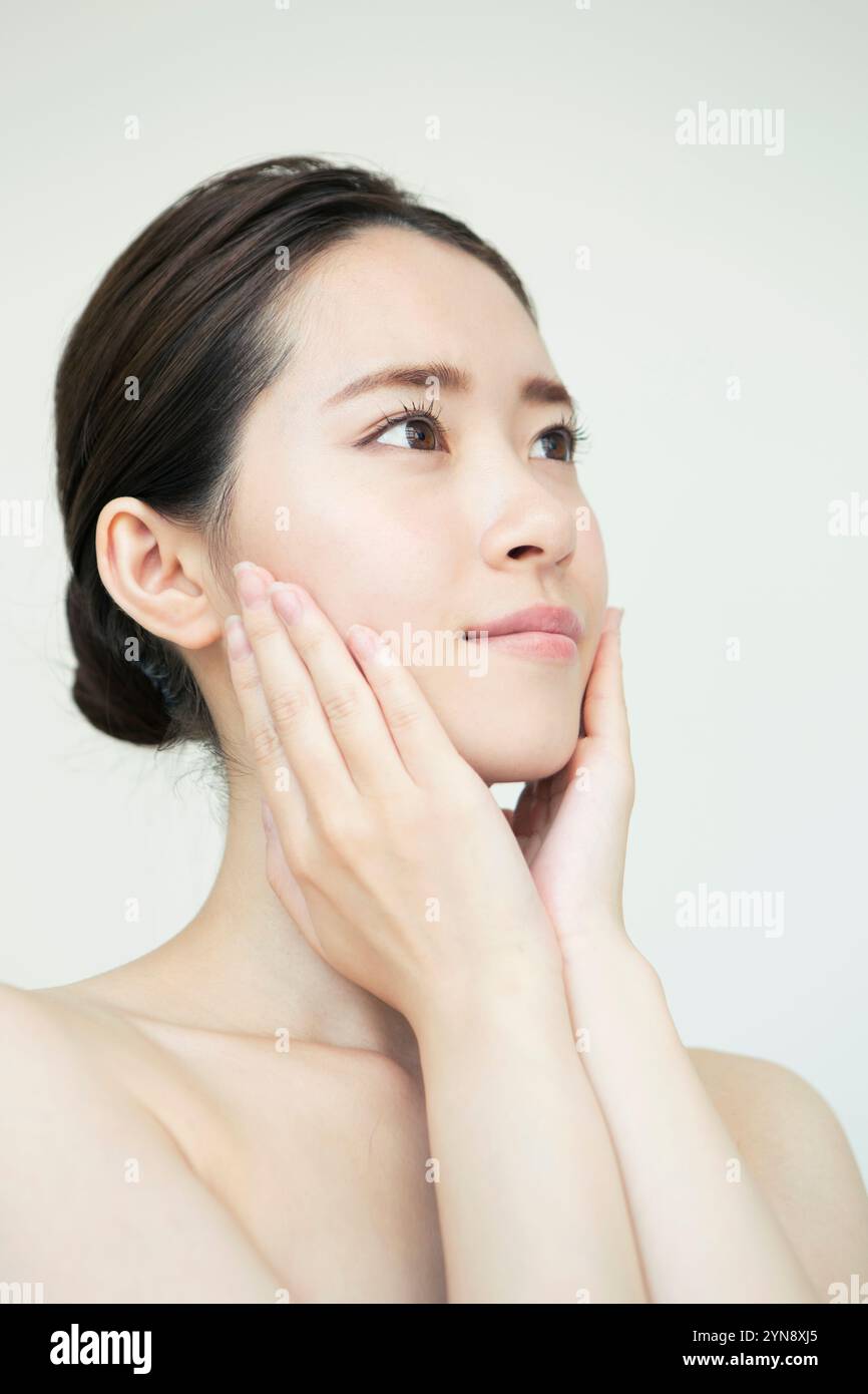 Woman in her 20s looking up with hand on cheek Stock Photo - Alamy