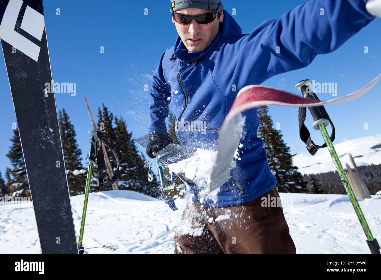 A male skier pulls the skins off his skis as he prepares for a mid ...
