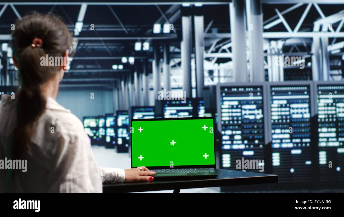Certified IT programmer in server farm housing high end clusters capable of quickly and efficiently performing complex computations and data analysis, using mockup laptop to eliminate issues Stock Photo