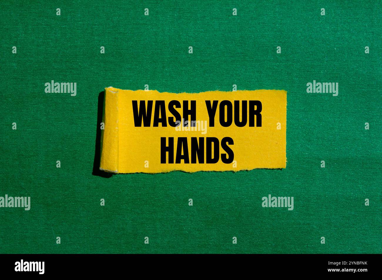 Wash your hands message written on ripped torn yellow paper piece with ...
