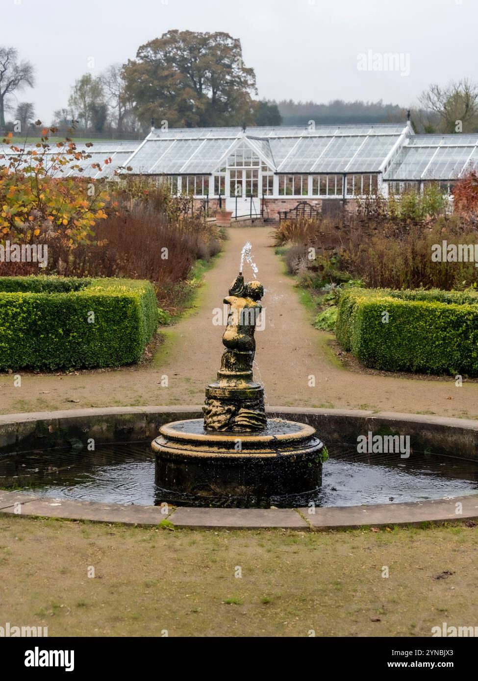 Fountain at Helmsley Walled Garden seen against the backdrop of the Victorian glasshouse. North Yorkshire. UK. Stock Photo