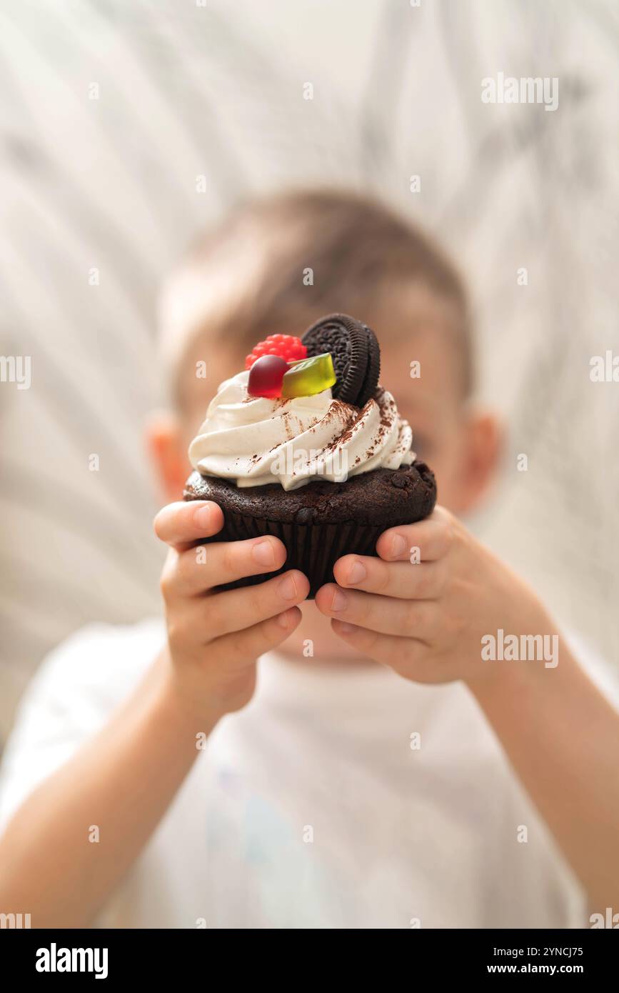 The boy holds a mini cake in his hands. Stock Photo