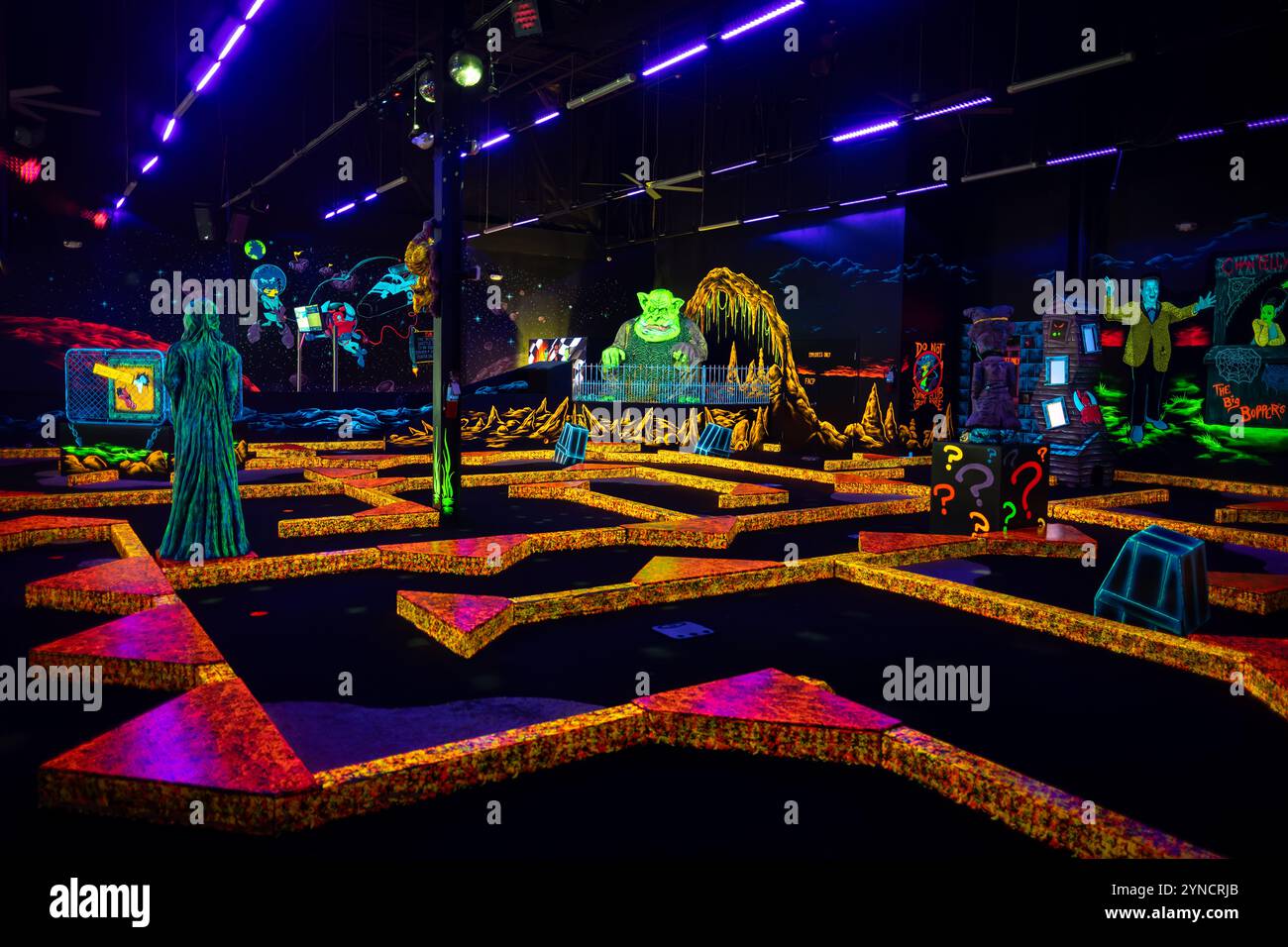 Monster Mini Golf Interior Chantilly Virginia // CHANTILLY, Virginia — The interior of Monster Mini Golf features vibrant UV-reactive decorations and neon artwork illuminated by blacklights throughout the indoor mini golf course. The facility combines monster-themed elements with fluorescent colors to create an immersive glow-in-the-dark putting experience. Stock Photo