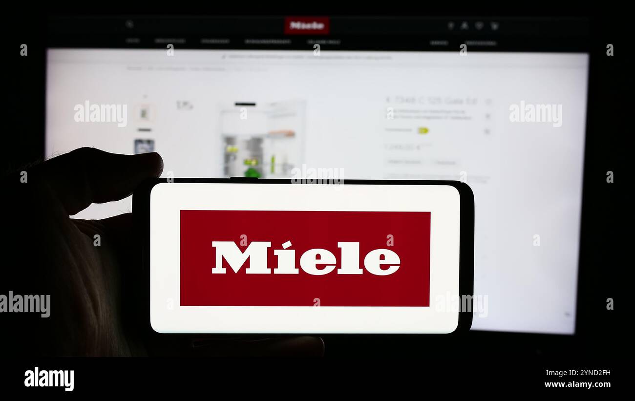 Germany. 5th Aug, 2024. In this photo illustration, a person is holding a cellphone with the logo of German household appliances company Miele Cie. KG in front of business webpage. (Credit Image: © Timon Schneider/SOPA Images via ZUMA Press Wire) EDITORIAL USAGE ONLY! Not for Commercial USAGE! Stock Photo