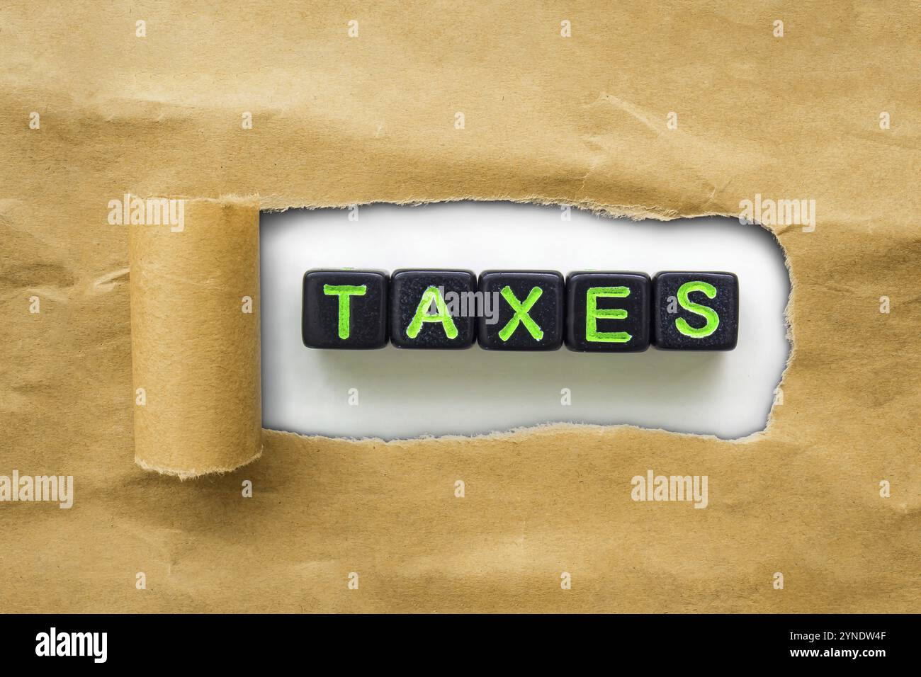 Brown package kraft paper torn to reveal black cubes with the word TAXES. Concept tax season Stock Photo