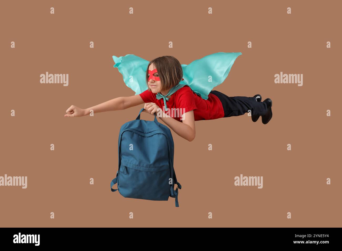 Happy schoolboy dressed as superhero with backpack flying on brown ...