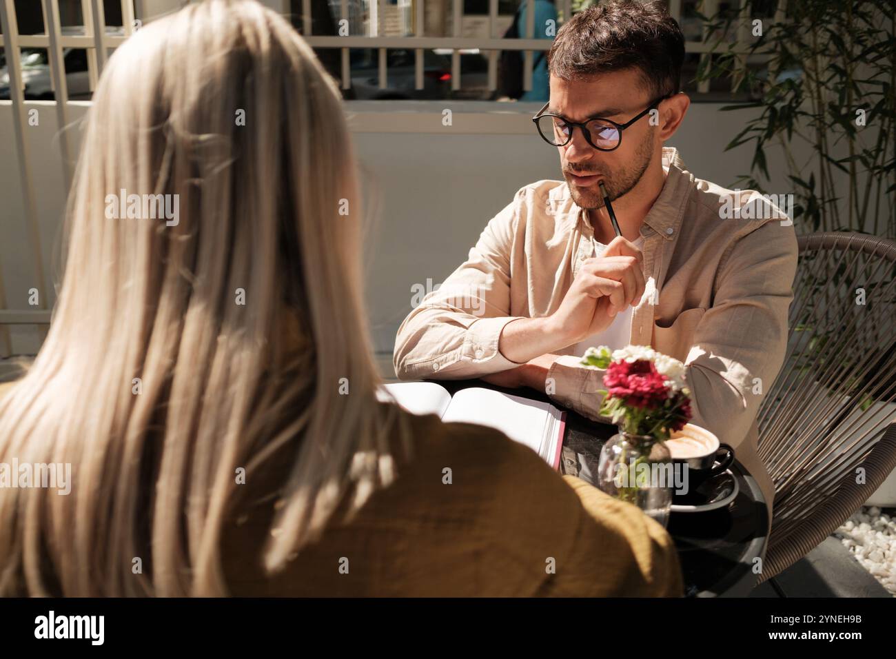 Casual meeting between colleagues discussing work in a cozy outdoor cafe Stock Photo