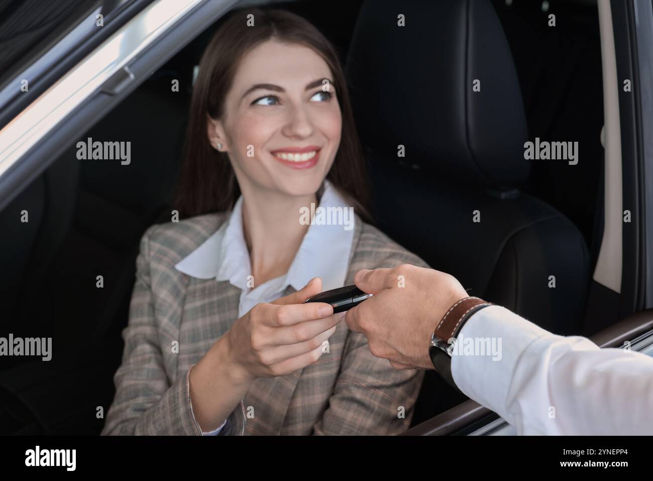Salesman giving key to client inside new car in salon Stock Photo - Alamy