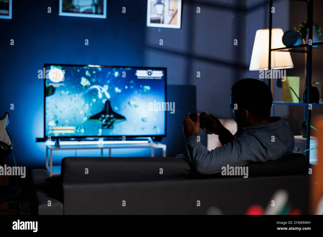 At home, console player competes in shooting gameplay engaging in ...