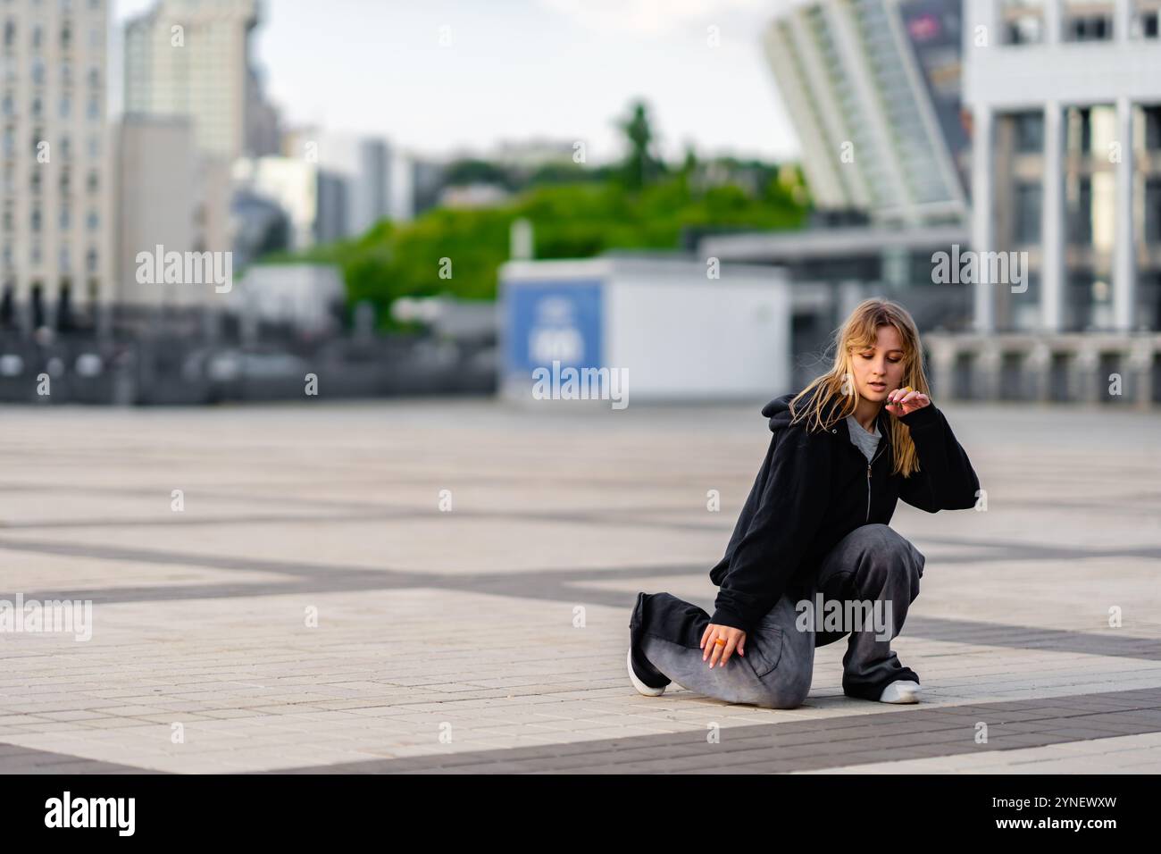 Young dancer practicing movements on urban plaza during daylight hours Stock Photo