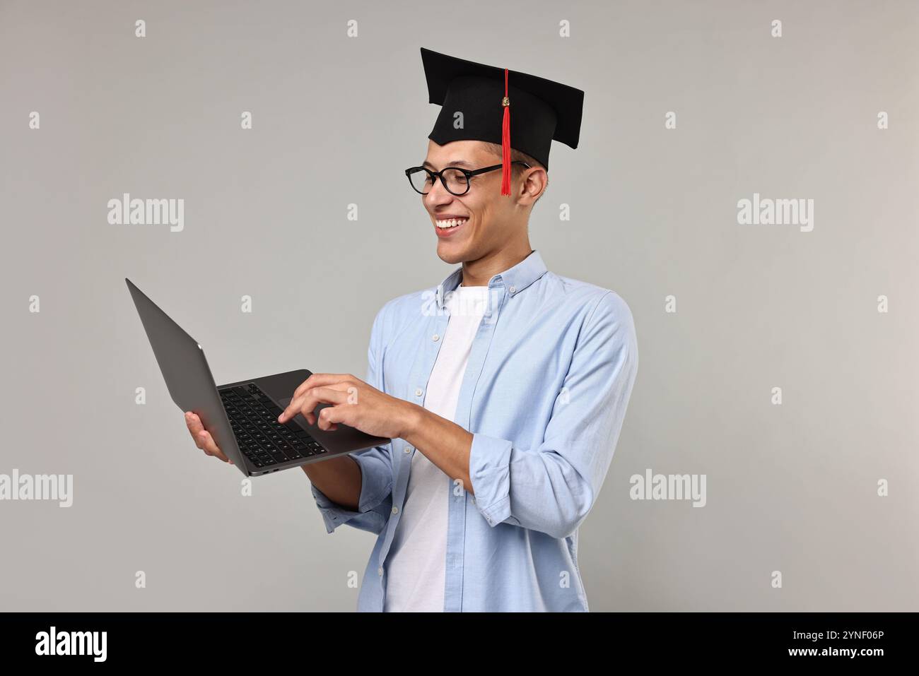 Happy student with laptop after graduation on grey background Stock ...