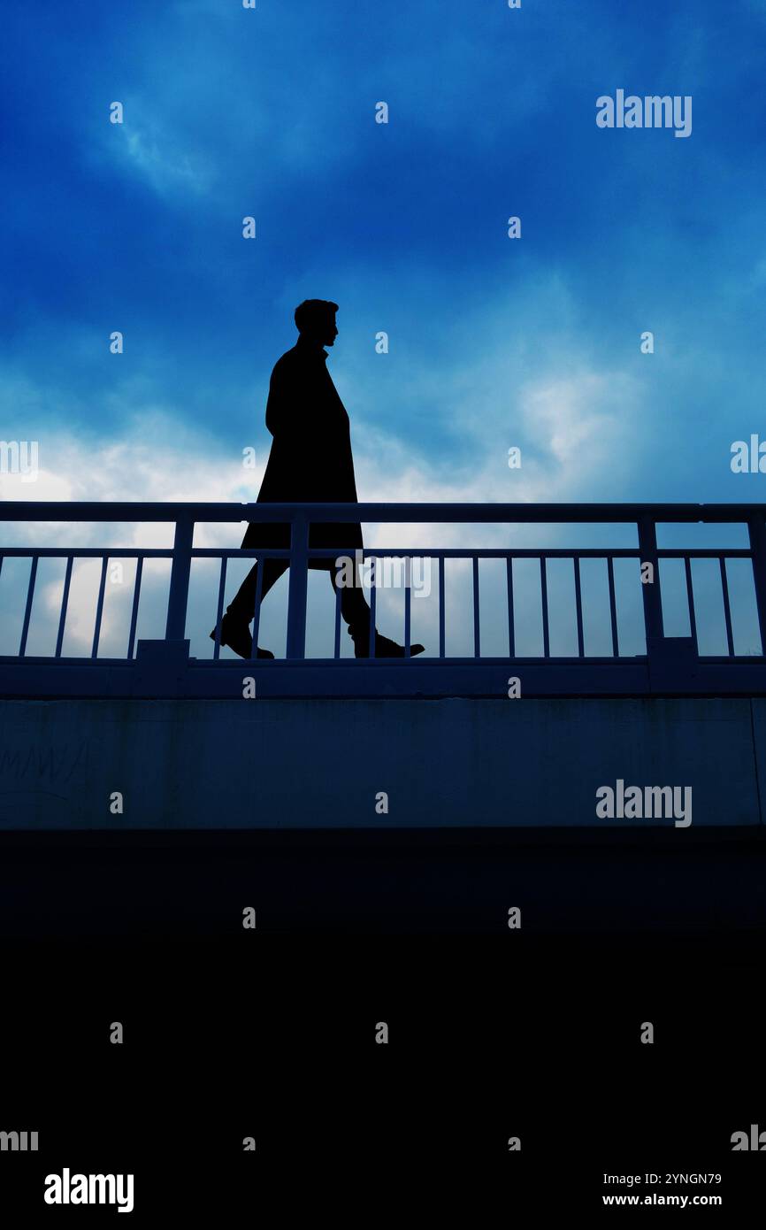 silhouette of a man walking on a bridge Stock Photo - Alamy