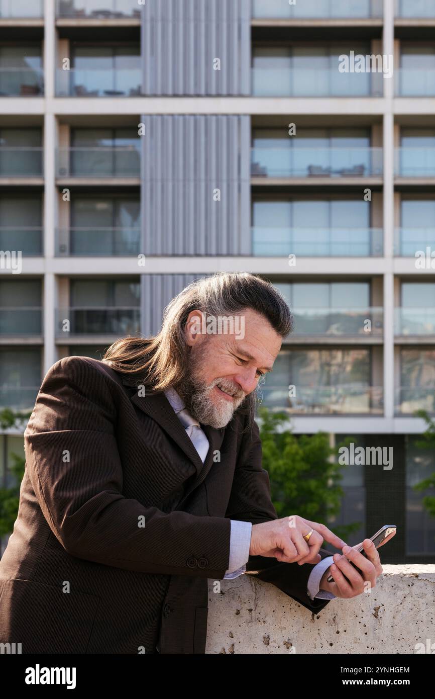 mature man in classy suit browsing on smartphone Stock Photo