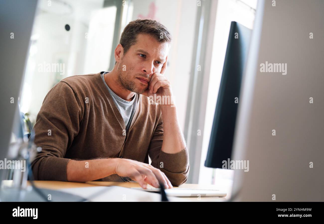 Portrait of a disappointed man programmer looking stressed out while working on a computer code Stock Photo