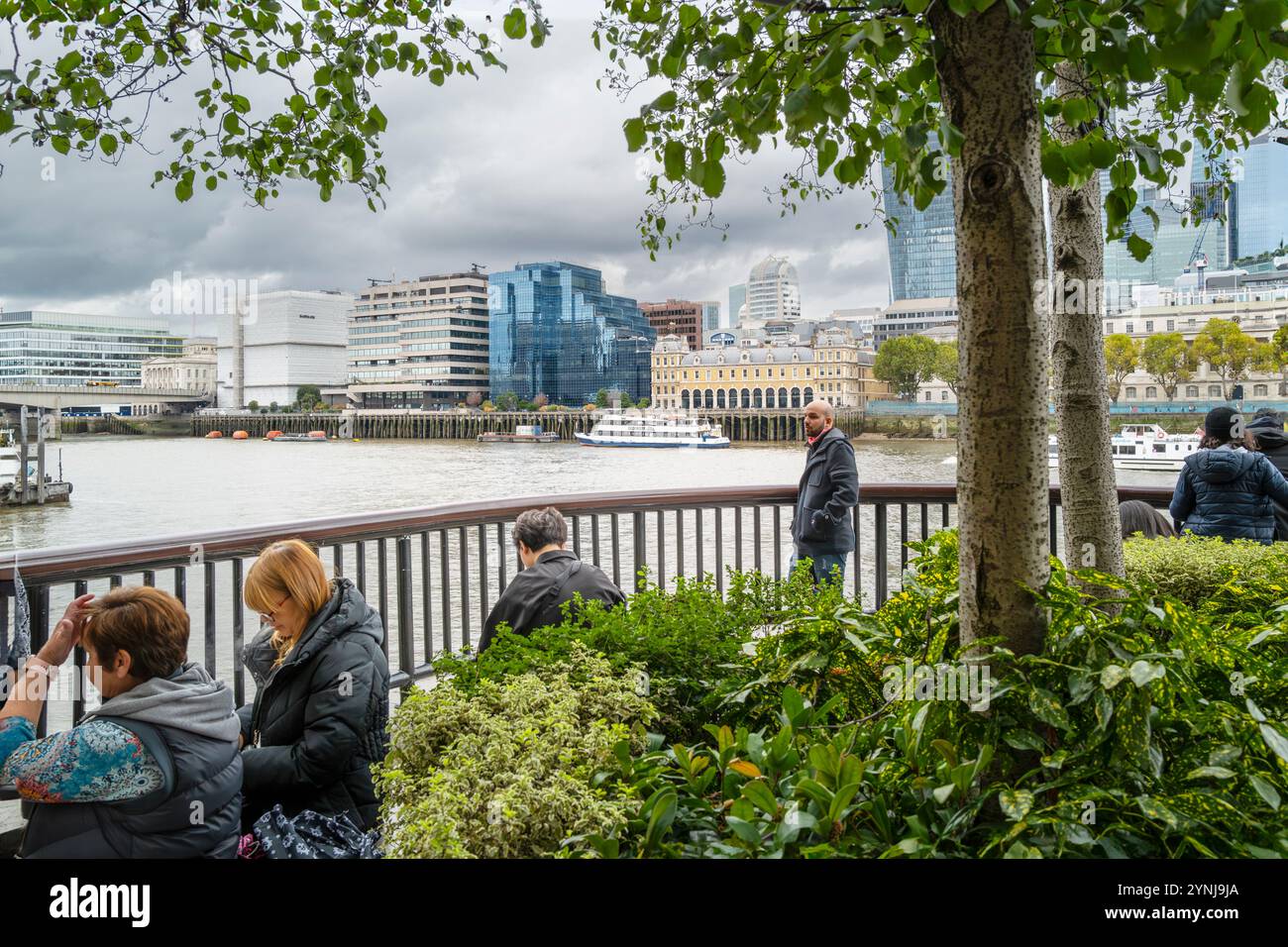 People relaxing on the South Bank looking out over the River Thames in London in the UK in Europe. Stock Photo