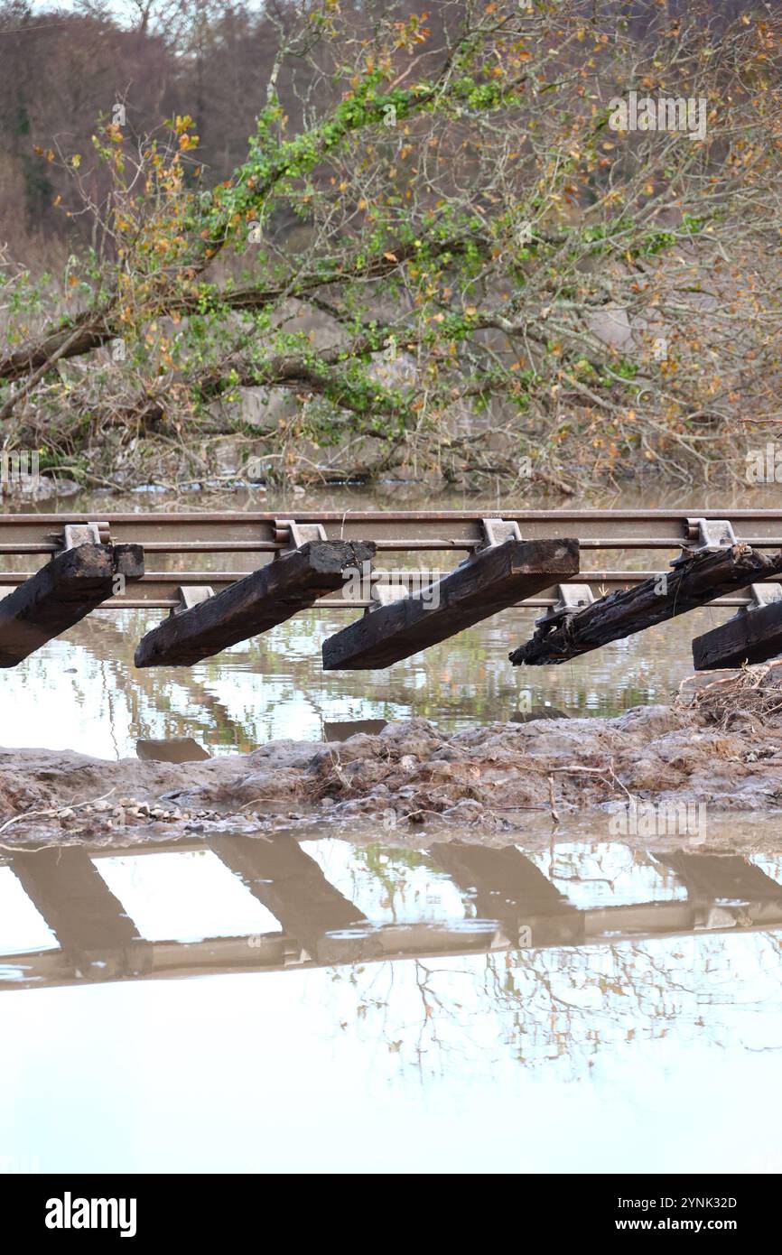 Stover Canal, Newton Abbot, Devon, UK. 26th Nov, 2024. UK Weather: Storm Bert aftermath rail track dangling as path washed away following heavy snow and floods at Stover Canal, Newton Abbot, Devon. The cycle path; footpath and rail track will be closed until further notice Credit: nidpor/Alamy Live News Stock Photo