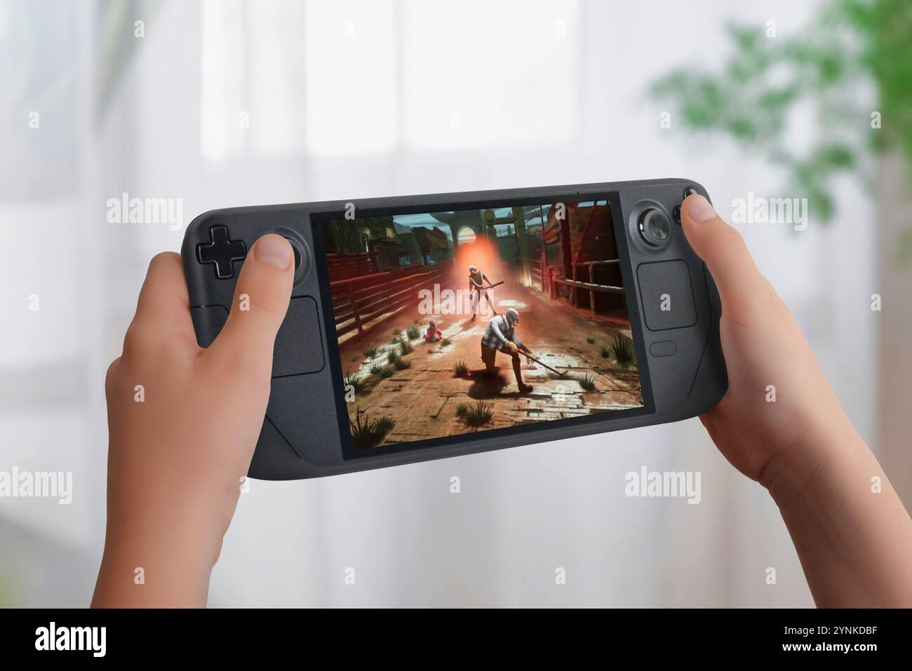 Child holding a handheld gaming console displaying an action game, emphasizing the concept of usability and growth of compact consoles in the global m Stock Photo