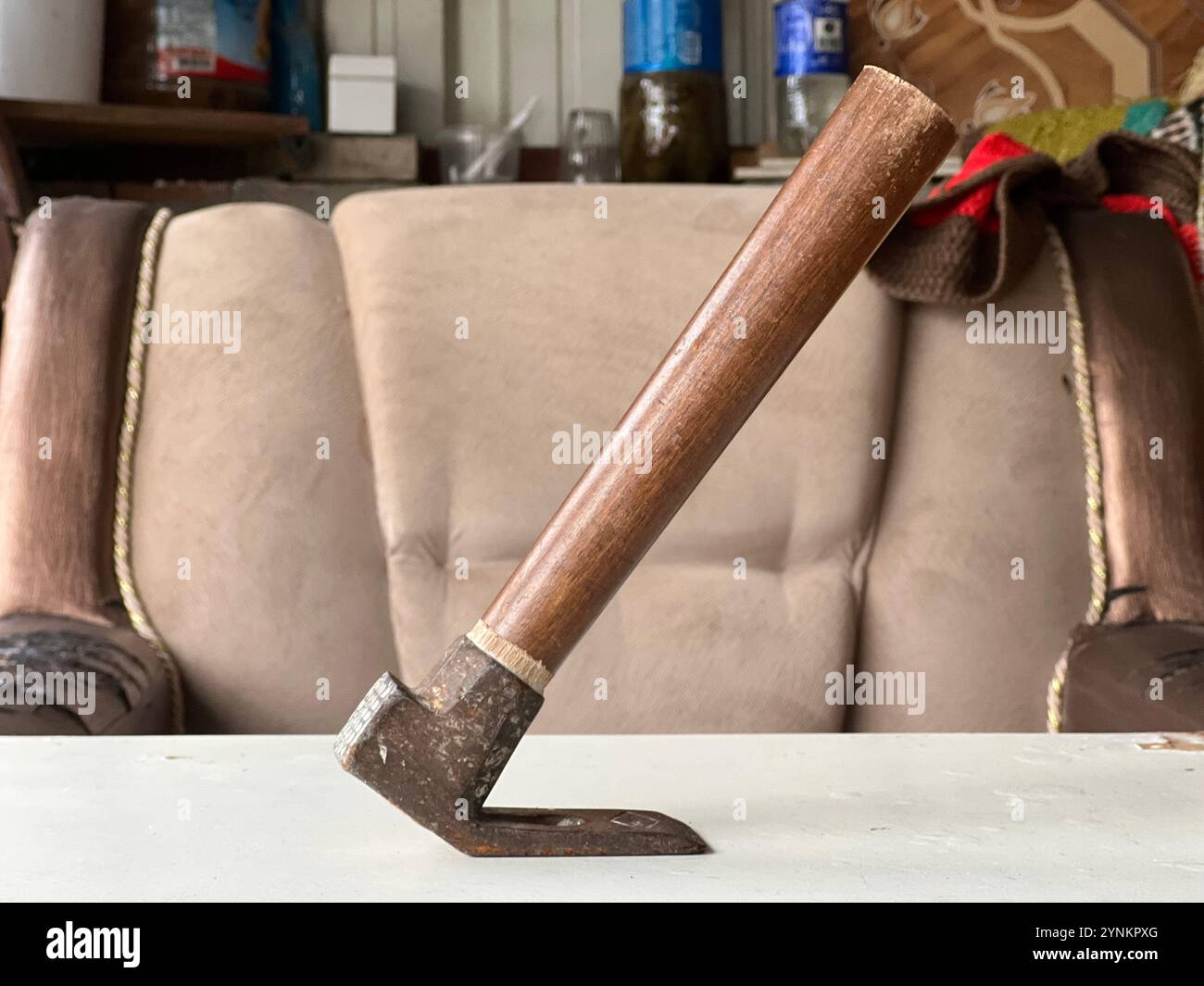 A hand tool with a wooden handle rests on a table in a workshop setting. Stock Photo