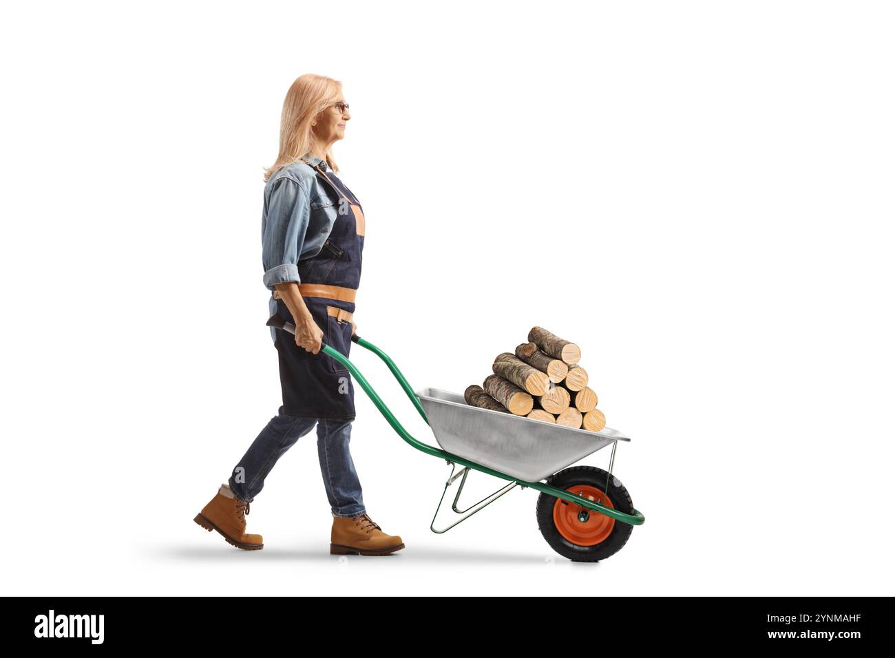 Full length profile shot of a female farmer pushing a wheelbarrow with ...