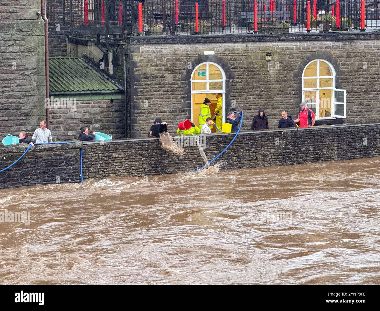 Pontypridd, Wales, UK - 24 November 2024: Volunteers using buckets and bins to bail out water from the basement of the town's museum - Smartphone Captured Stock Image