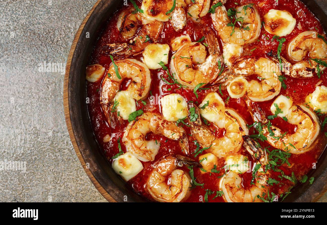 Saganaki with shrimp, in a clay pan, Greek dish, shrimp in tomato sauce ...