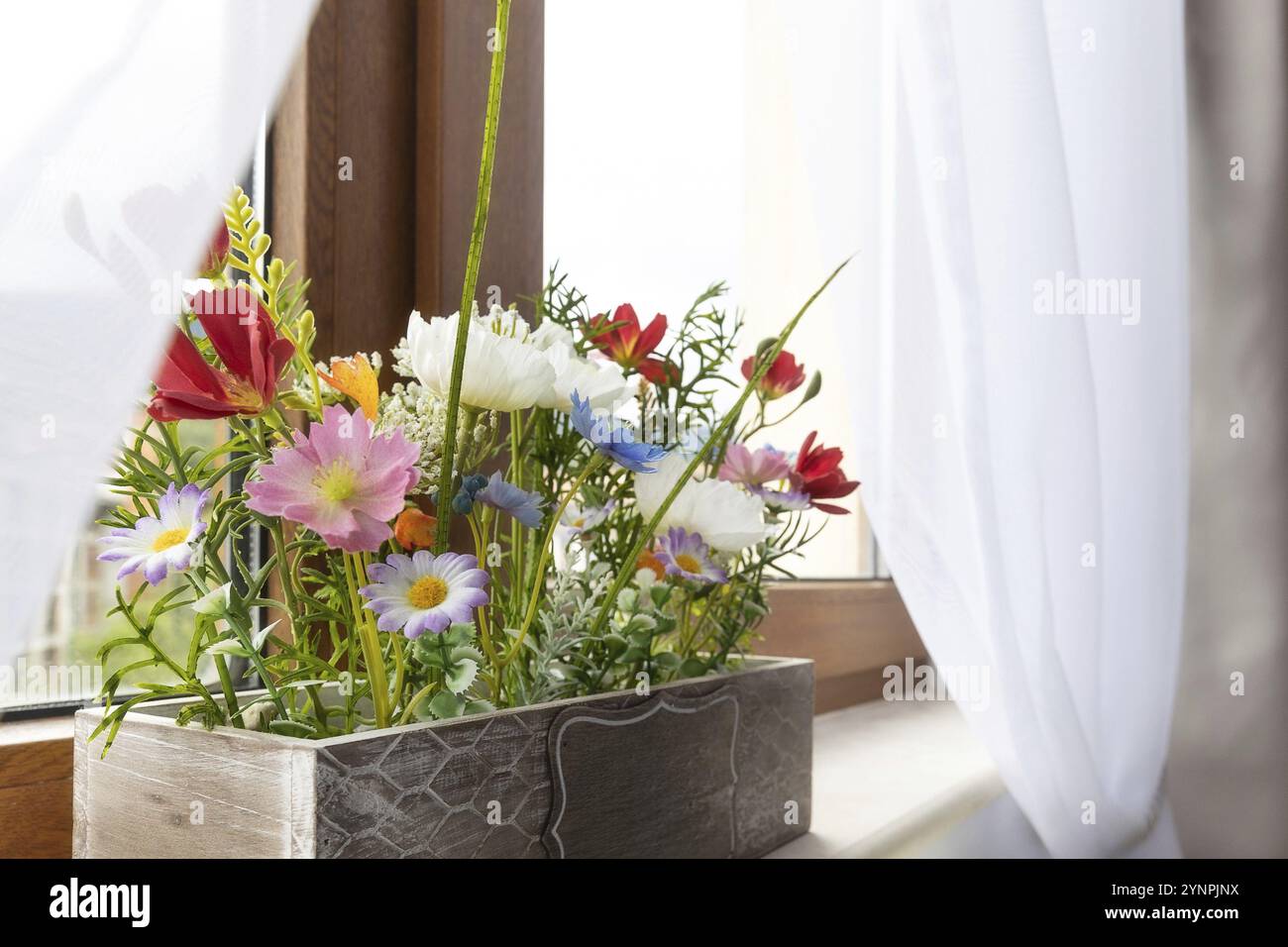 Artificial plant colorful flower in flowerpot on window sill indoors, interior design Stock Photo