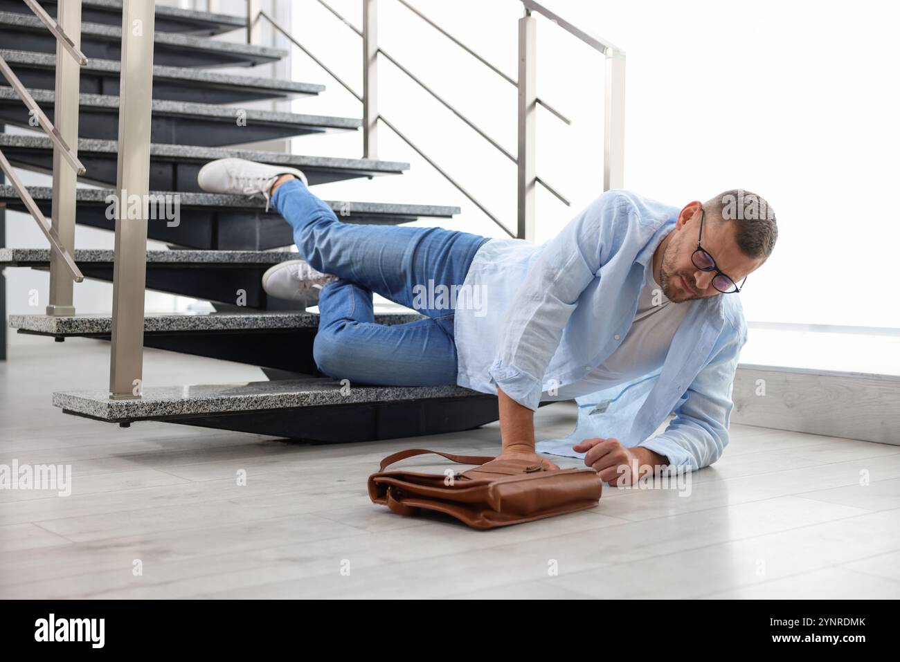 Injured man on stairs in building after fall. Dangerous accident Stock ...