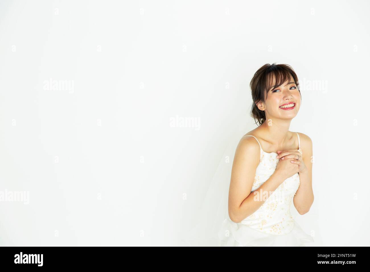 Bride in her 20s in wedding dress with hand on chest Stock Photo - Alamy