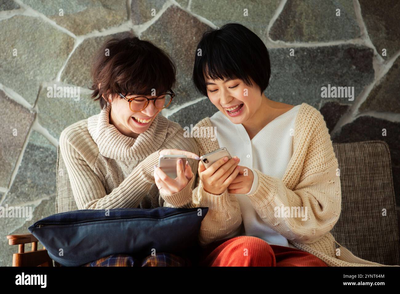 Two women in their 20s enjoying looking at their phones Stock Photo - Alamy