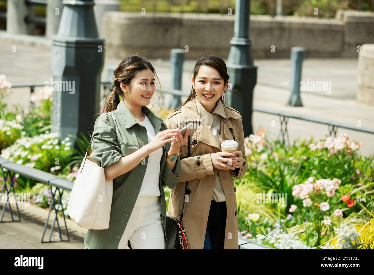 Two women in their 20s walking down the street smiling Stock Photo - Alamy