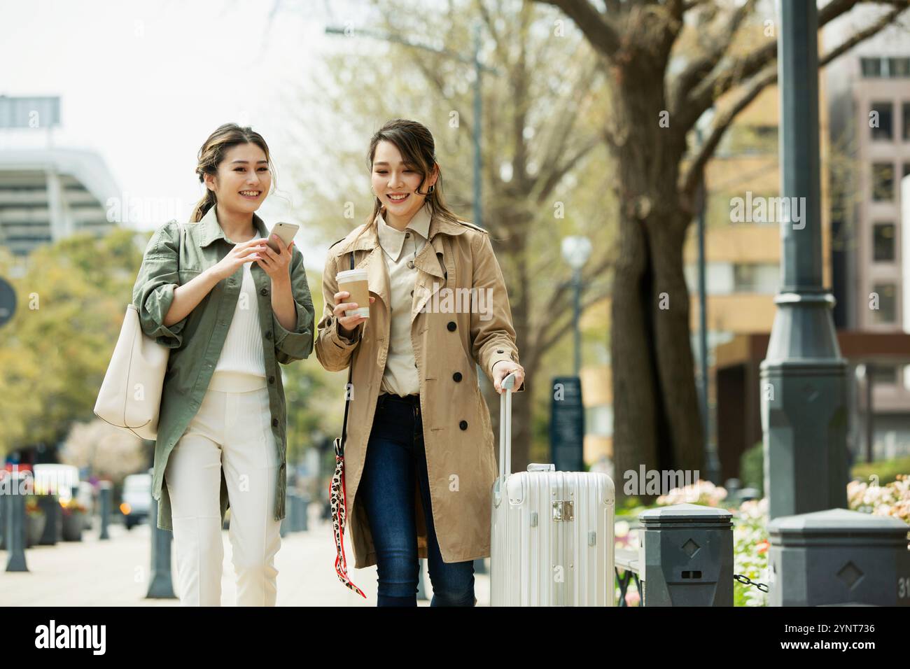 Two women in their 20s walking down the street smiling Stock Photo - Alamy