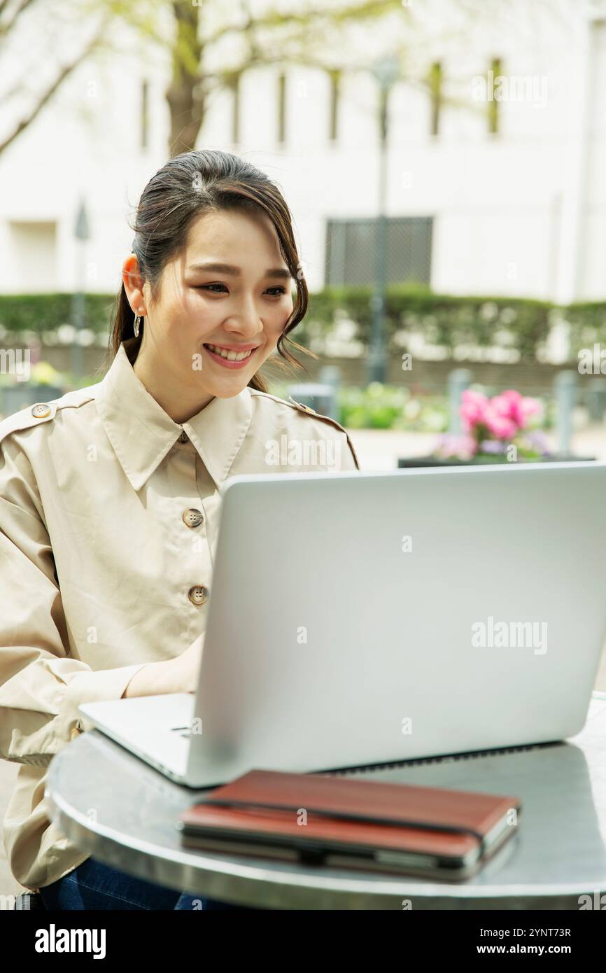 Woman in her 20s using a computer on the terrace Stock Photo - Alamy