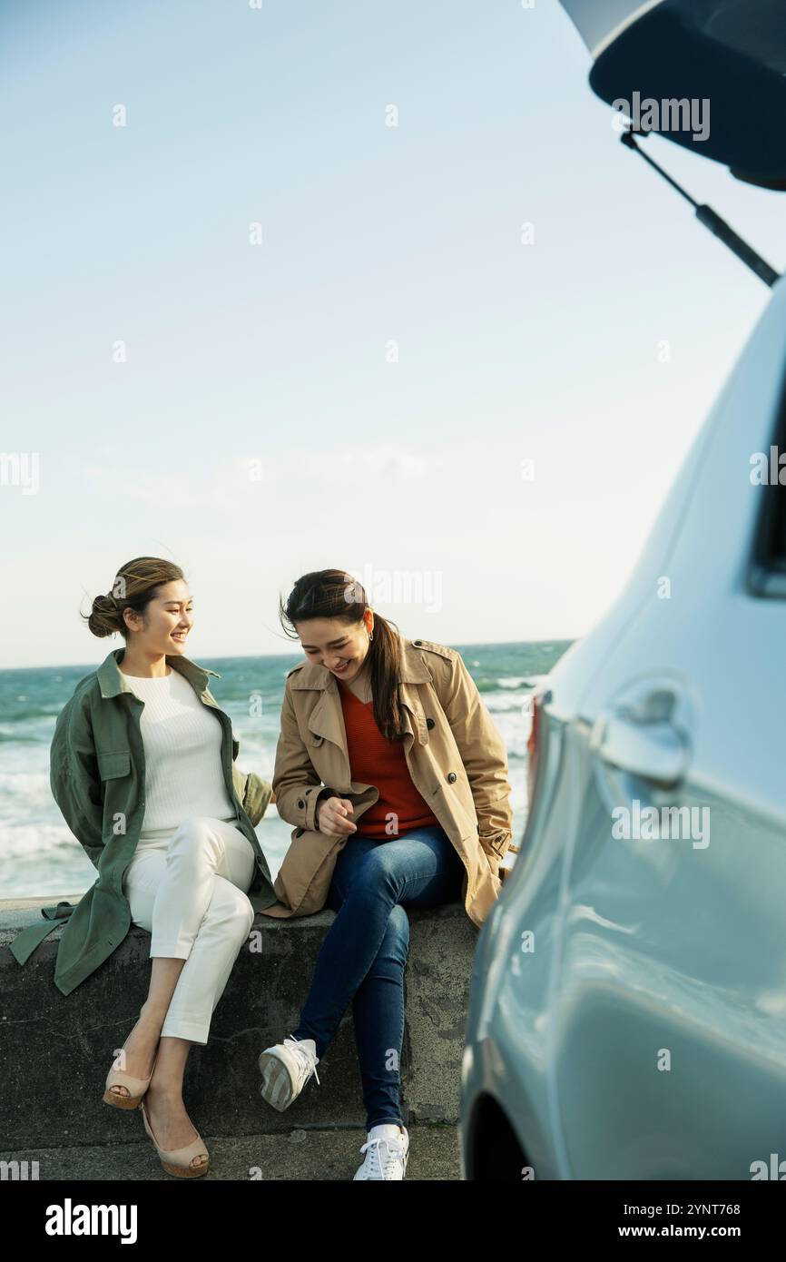Two happy women in their 20s talking by the sea Stock Photo - Alamy
