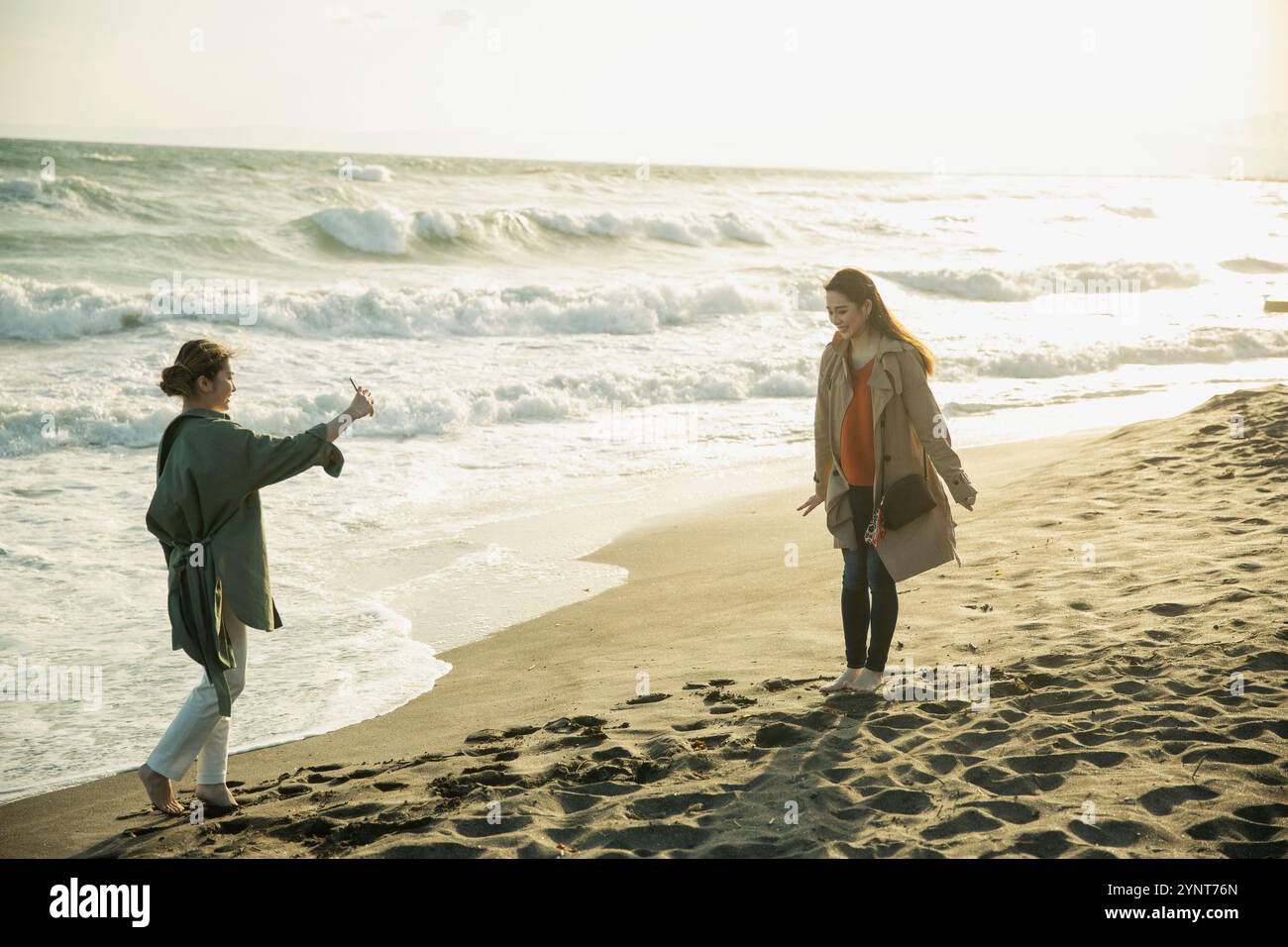 Two women in their 20s enjoying a walk in the surf Stock Photo - Alamy